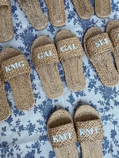 several pairs of slippers with the word cat camp written on them sitting on a blue and white flowered cloth