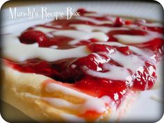 a close up of a piece of food on a plate with white sauce and strawberries