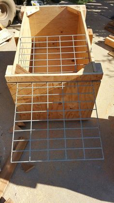 a wooden box sitting on top of a pile of wood next to some metal bars