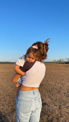 two girls hugging each other in the middle of an open field with blue sky behind them