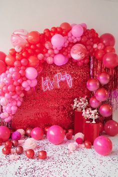 balloons and confetti surround the backdrop for a party