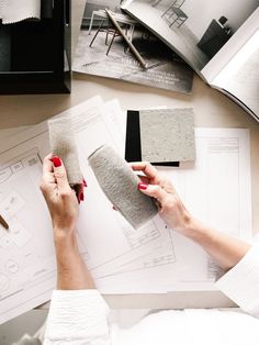 a woman is working on some type of project with her hands and papers around her