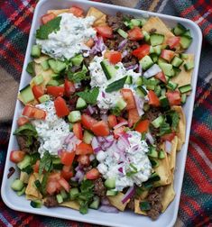 a tray filled with nachos and vegetables on top of a blanket