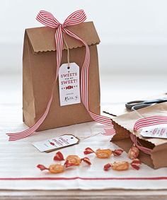 a brown paper bag with a red ribbon on it and some nuts in front of it