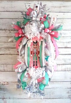 a christmas wreath hanging on the side of a wooden wall with ribbons and ornaments around it