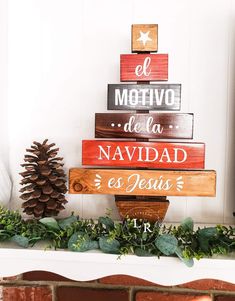 a wooden christmas tree sitting on top of a mantle next to a pine cone and evergreen