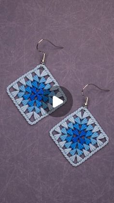 a pair of blue and white crocheted square earrings with silver hooks hanging from them