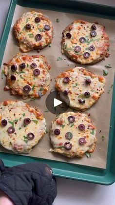 a tray filled with mini pizzas covered in cheese and olives