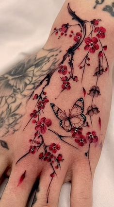 a woman's hand with red flowers and butterflies on it