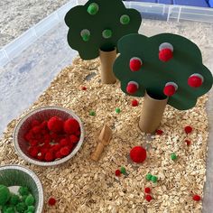 three paper trees with pom - poms on them and two bowls full of strawberries