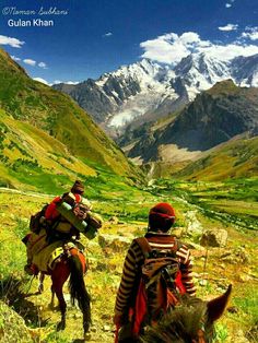 two people riding horses in the mountains with snow capped peaks behind them and green valley below