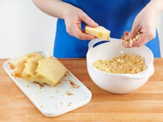 a person in blue shirt and white bowl with food on wooden table next to cutting board