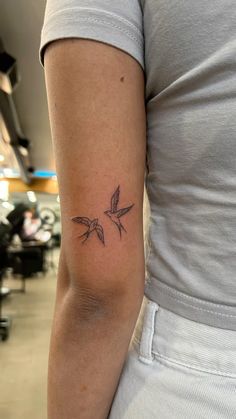 a woman's arm with a small bird tattoo on the back of her left arm