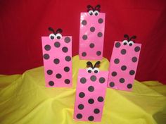 pink and black paper bags with ladybugs on them sitting on a yellow cloth