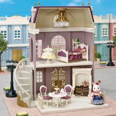 a doll house with furniture and accessories in the front, stairs leading up to the second floor