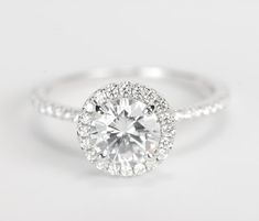 a white gold engagement ring with diamonds on the band and a round center stone in the middle