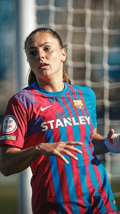 a female soccer player wearing a red and blue uniform is in front of the goal