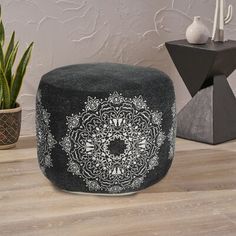 a black ottoman sitting on top of a wooden floor next to a potted plant