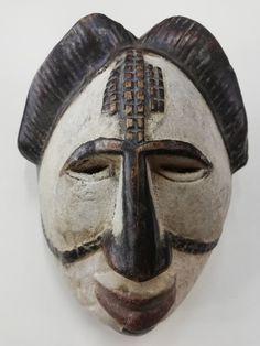 an african mask is displayed on a white surface