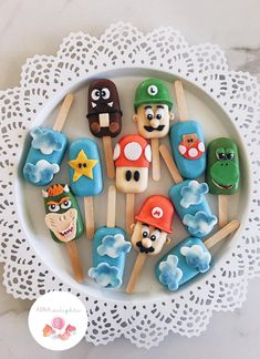 there are many cookies that look like mario bros on the stick in the plate with other items