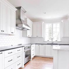 an empty kitchen with white cabinets and wood floors