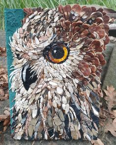 an owl made out of seashells sitting on the ground