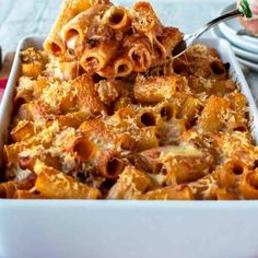 a person scooping some pasta from a casserole dish