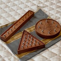 two pieces of wood sit on top of a quilted surface with silver studs