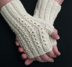 a pair of white knitted arm warmers on a person's hand,