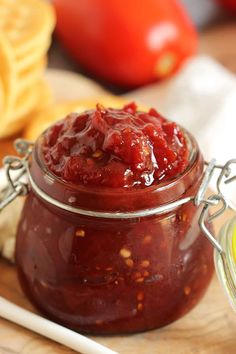 a glass jar filled with ketchup sitting on top of a wooden cutting board