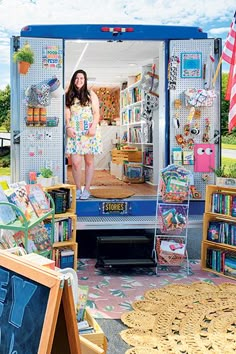 a woman standing in the back of a truck filled with lots of books and toys