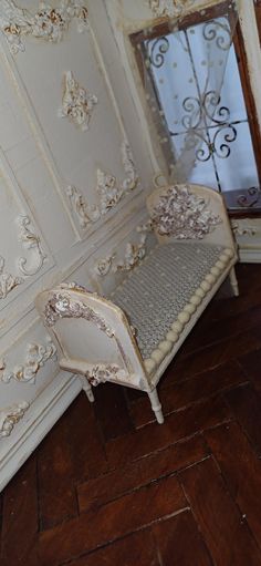 a white couch sitting on top of a hard wood floor next to a wall covered in peeling paint