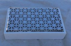 a white box sitting on top of a table covered in silver foil and geometric designs