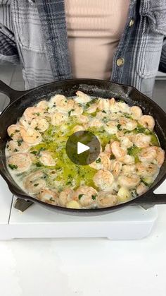 a woman cooking shrimp in a skillet on the stove