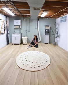 a woman sitting on the floor in front of a rug