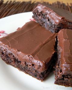 chocolate brownies with frosting on a white plate