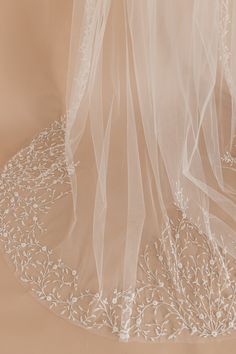 the veil is hanging from the back of a bridal gown with white flowers on it