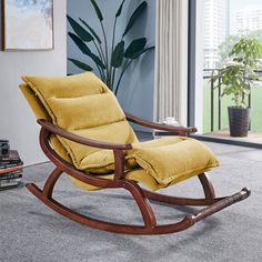 a wooden rocking chair with yellow cushions in a living room next to a large window