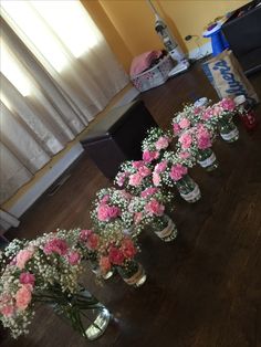 pink and white flowers in vases lined up on the floor next to a window