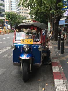 an auto rickshaw is parked on the side of the road in front of a tree