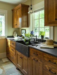 a kitchen with wooden cabinets and black counter tops next to a window in the corner