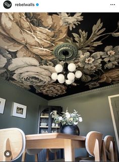 a dining room table and chairs under a painted ceiling with flowers on the wall above it