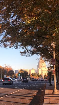 cars are driving down the street in front of an old building with a dome on top