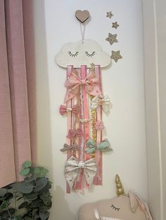 there is a wall decoration made out of ribbons and bows on the wall next to a potted plant