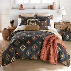 a bed in a bedroom with pillows and blankets on top of the bedspread