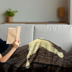 a woman sitting on a couch reading a book