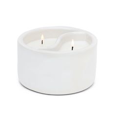 two white candles sitting inside of a bowl