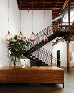 a wooden table sitting under a staircase next to a plant