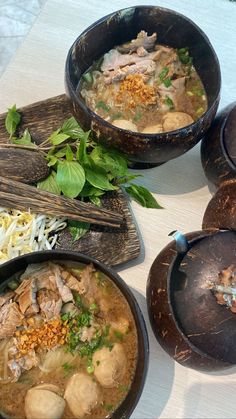 three bowls filled with food sitting on top of a white table next to chopsticks