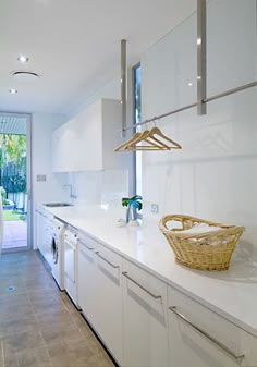 a kitchen with white cabinets and counter tops next to an open door that leads to a patio